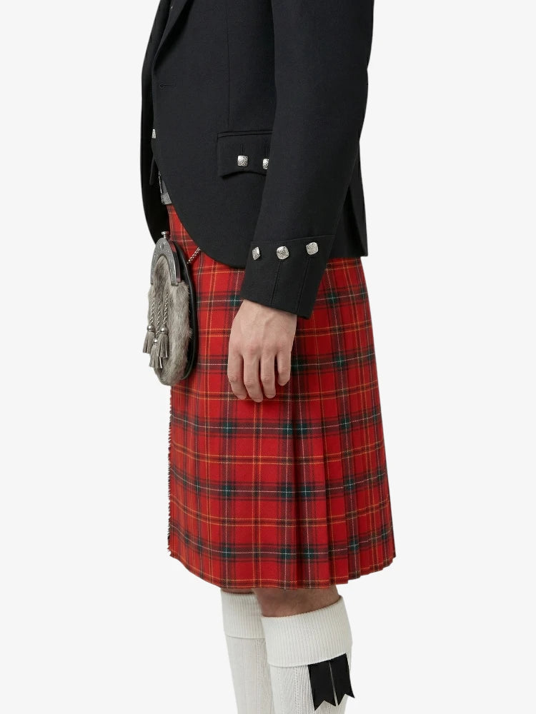 Person wearing a red tartan kilt with a black jacket on a white background