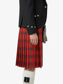 Person wearing a red plaid kilt with a black jacket on a white background