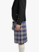 Person wearing a black jacket and blue plaid kilt on a white background