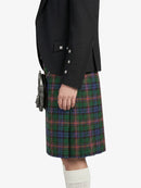Person wearing a black jacket and plaid kilt on a white background