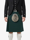 Person wearing a traditional Scottish kilt with a dark jacket and white socks on a light gray background