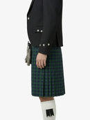 Person wearing a black jacket and green plaid kilt on a white background