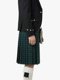 Person wearing a black jacket and green plaid kilt on a white background