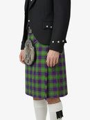 Person wearing a black jacket, green and purple plaid kilt, and white knee-high socks on a white background