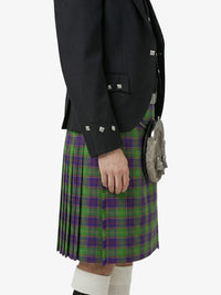 Person wearing a green and purple plaid kilt with a black jacket and sporran on a white background