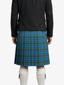 Person wearing a black jacket and blue plaid kilt on a white background