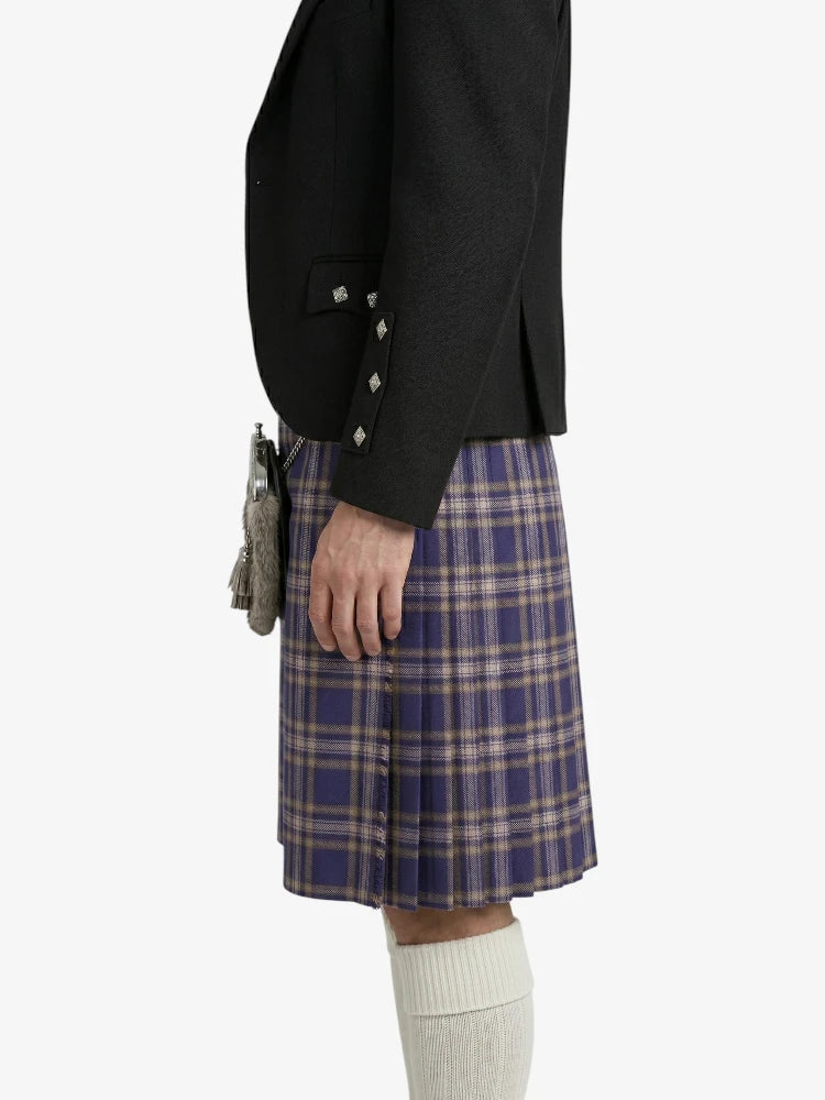 Person wearing a black blazer and plaid kilt on a white background