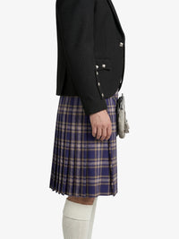 Person wearing a black blazer and plaid kilt on a white background