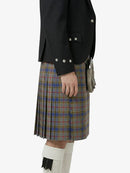 Person wearing a black jacket and plaid kilt on a white background