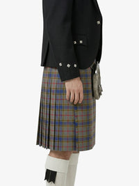 Person wearing a black jacket and plaid kilt on a white background
