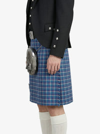 Person wearing a black jacket, blue plaid kilt, and white knee-high socks on a white background