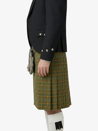 Person wearing a black jacket and green plaid kilt on a white background