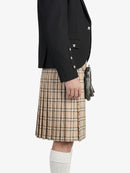Person wearing a black jacket and beige plaid kilt on a white background