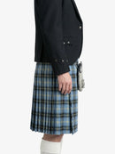 Person wearing a black jacket and blue plaid kilt on a white background