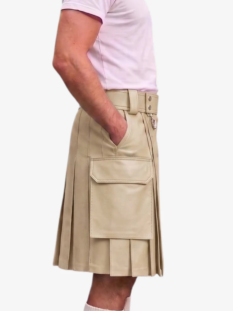A person wearing a beige faux-leather kilt with pleated detailing, a belt, and a large front cargo pocket, paired with a light pink t-shirt against a plain white background.