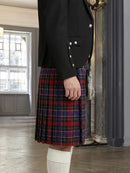 Person wearing a black jacket and red plaid kilt indoors.