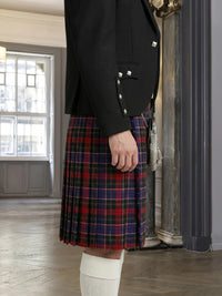 Person wearing a black jacket and red plaid kilt indoors.
