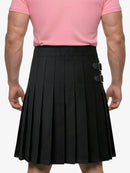 Person wearing a black pleated skirt with silver buckles and a pink shirt on a white background