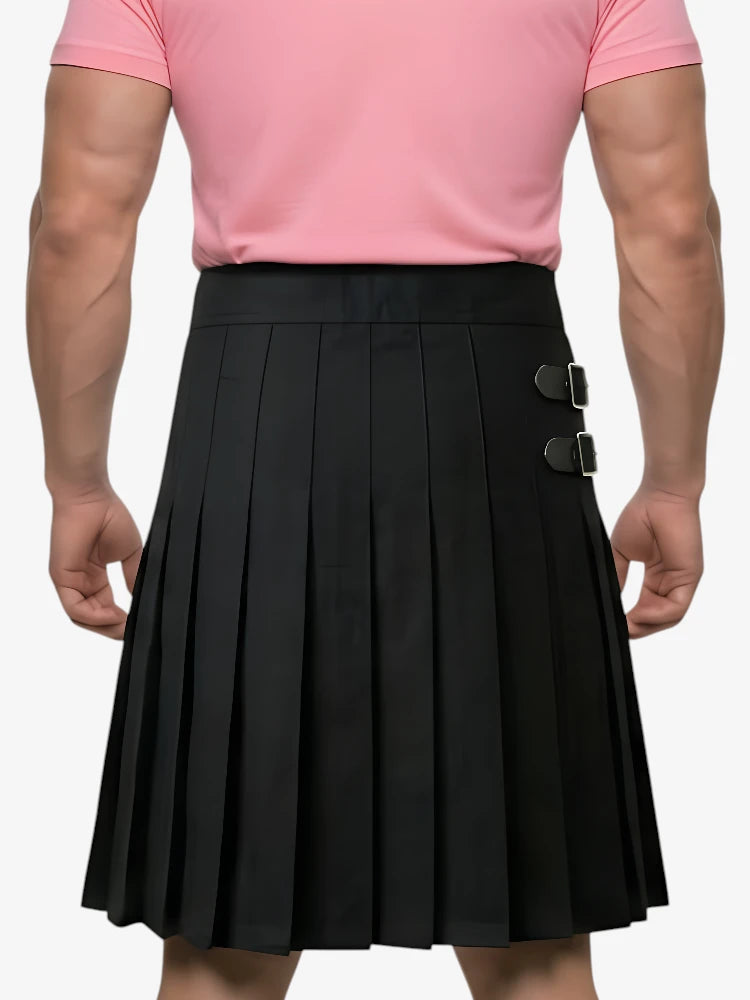 Person wearing a black pleated skirt with silver buckles and a pink shirt on a white background