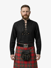 Man wearing a black shirt with lace-up front and a red plaid kilt on a white background