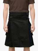 Person wearing a black kilt with plaid accents on a white background