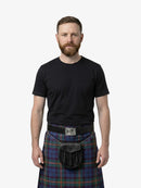 Man wearing a black t-shirt and plaid kilt on a white background