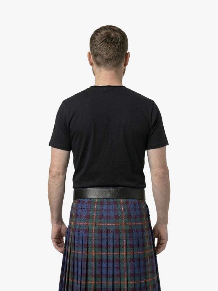 Man wearing a black t-shirt and a plaid kilt on a white background