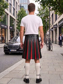 A man viewed from behind wearing a black leather kilt with red pleated stripes, a white t-shirt, white knee-high socks, and black shoes, standing on a city sidewalk.