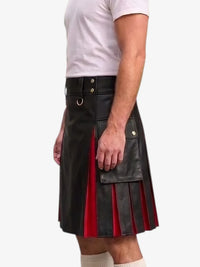 A man wearing a black faux-leather kilt with red pleated inserts and brass hardware, paired with a white t-shirt and white socks, shown from the waist down against a light gray background.