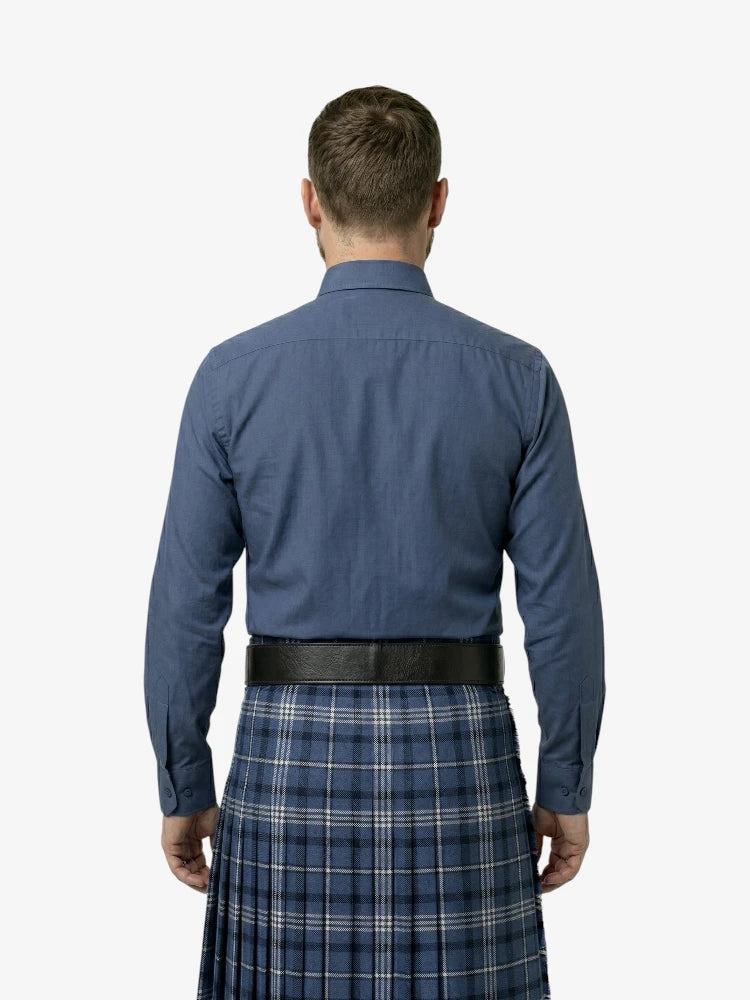 Man wearing a blue shirt and plaid kilt on a white background