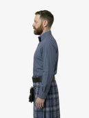 Man wearing a blue shirt and plaid kilt on a white background