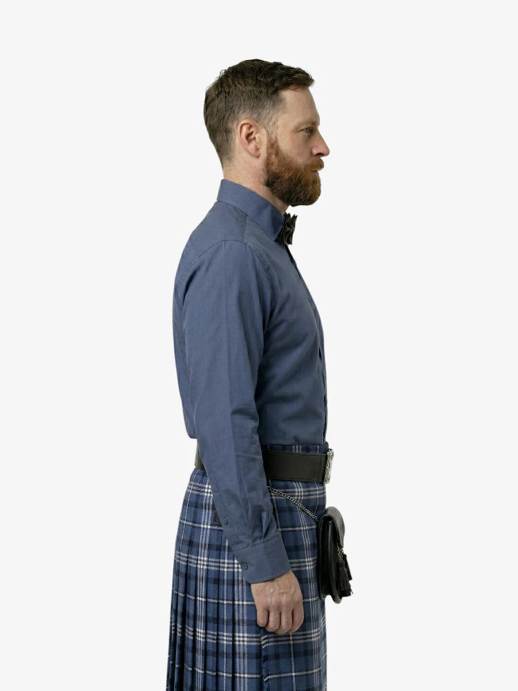 Man wearing a blue shirt and plaid kilt on a white background