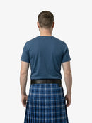 Man wearing a blue t-shirt and plaid kilt from behind on a white background