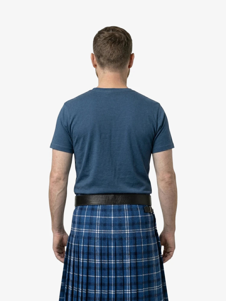 Man wearing a blue t-shirt and plaid kilt from behind on a white background