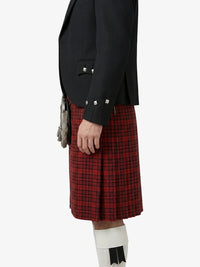 Person wearing a black jacket and red plaid kilt on a white background
