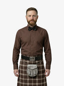 Man wearing a brown shirt, bow tie, and tartan kilt on a white background