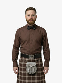 Man wearing a brown shirt, bow tie, and tartan kilt on a white background