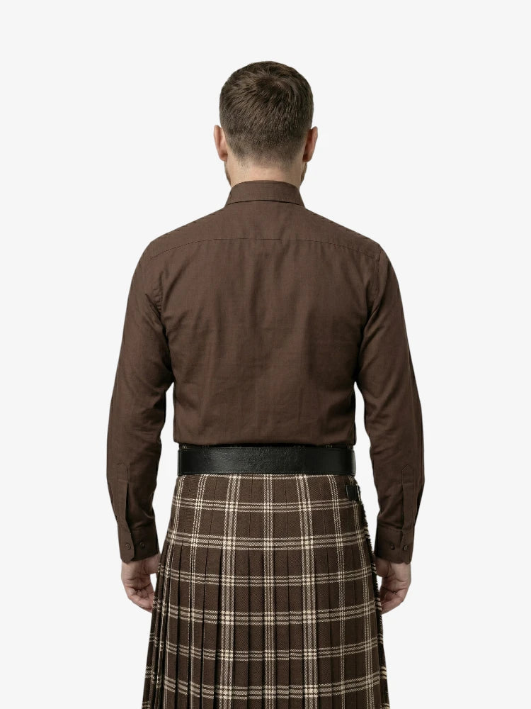 Man wearing a brown shirt and plaid kilt on a white background
