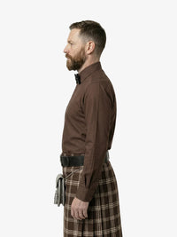 Man wearing a brown shirt and plaid kilt on a white background