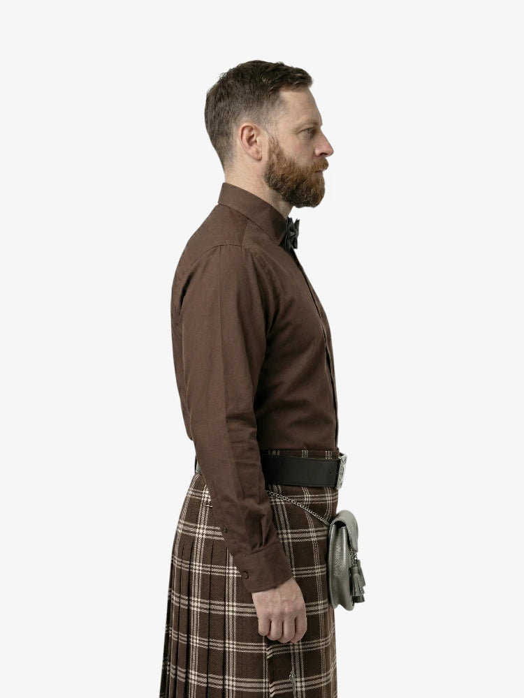 Man wearing a brown shirt and plaid kilt on a white background