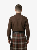 Man wearing a brown shirt and tartan kilt on a white background