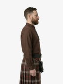 Man wearing a brown shirt and plaid kilt on a white background