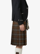 Person wearing a black jacket and brown plaid kilt on a white background