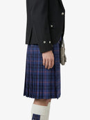 Person wearing a dark jacket and blue plaid kilt on a white background