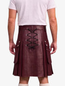 A person shown from the back wearing a pleated burgundy leather kilt with black lace-up detailing and silver-tone hardware, paired with a light pink t-shirt and white socks against a plain white background.