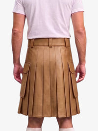 A person wearing a tan faux-leather pleated kilt with a matching belt and silver buckle, styled with a light pink t-shirt against a plain white background.