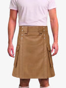 A person wearing a tan faux-leather kilt with silver-tone metal hardware and side cargo pockets, paired with a light pink t-shirt against a plain white background.
