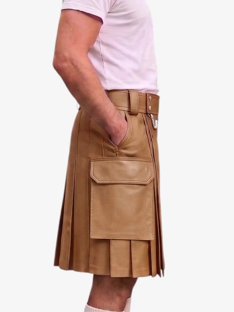 A person wearing a tan faux-leather pleated kilt with a matching belt and silver buckle, styled with a light pink t-shirt against a plain white background.