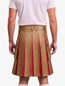 A person shown from the back wearing a tan pleated leather kilt with red inner lining and side flap pockets, paired with a light pink T-shirt against a plain light background.