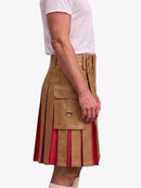 A side view of a person wearing a tan leather kilt with red pleated lining and brass hardware, paired with a white t-shirt and white socks, against a plain light gray background.